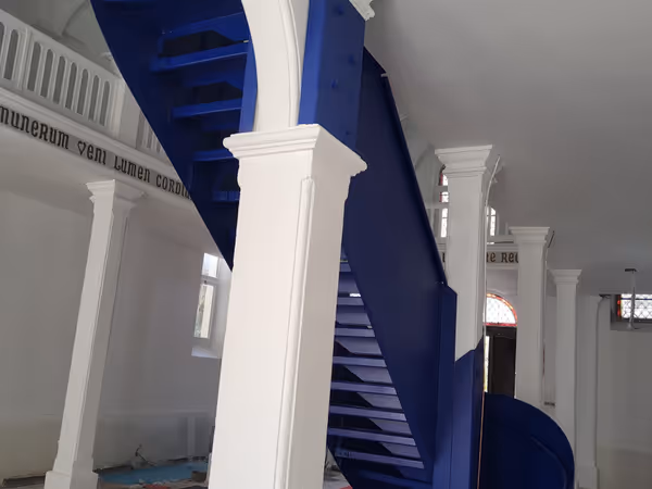 Double escalier monumental métallique suspendu bleu dans un hall historique