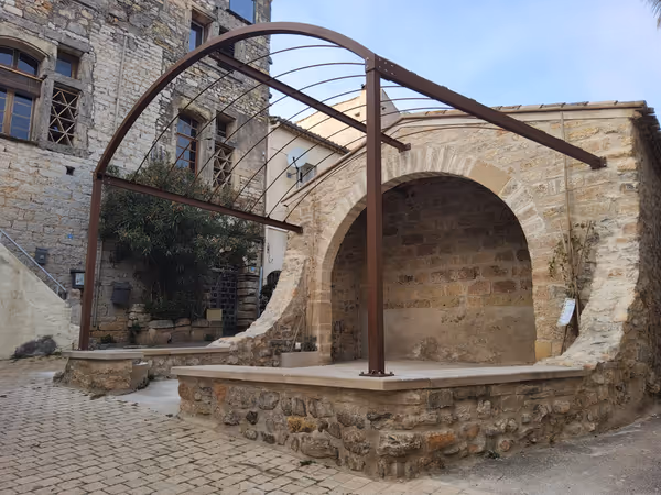 Pergola contemporaine en acier noir adossée à une maison en pierre